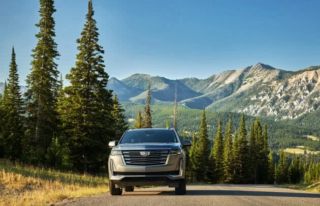 Cadillac in Big Sky, with pine trees and mountains in backdrop