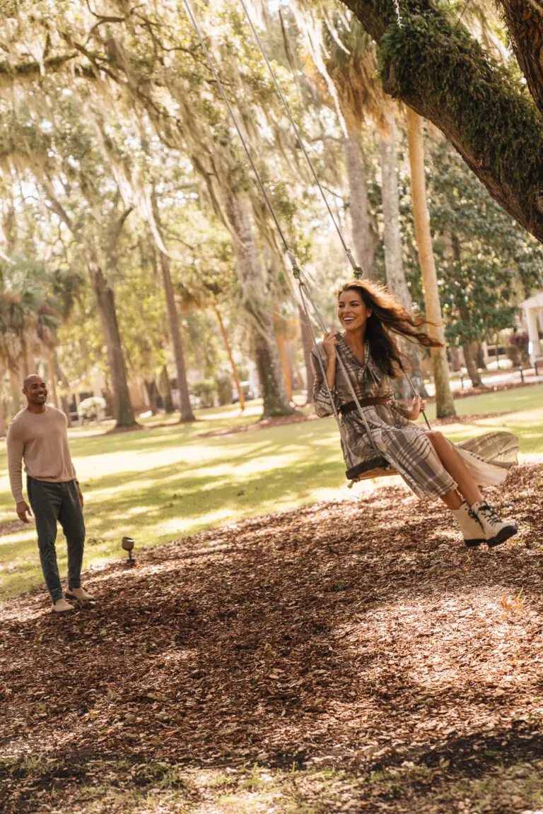 A man pushing a woman on a swing at Montage Palmetto Bluff