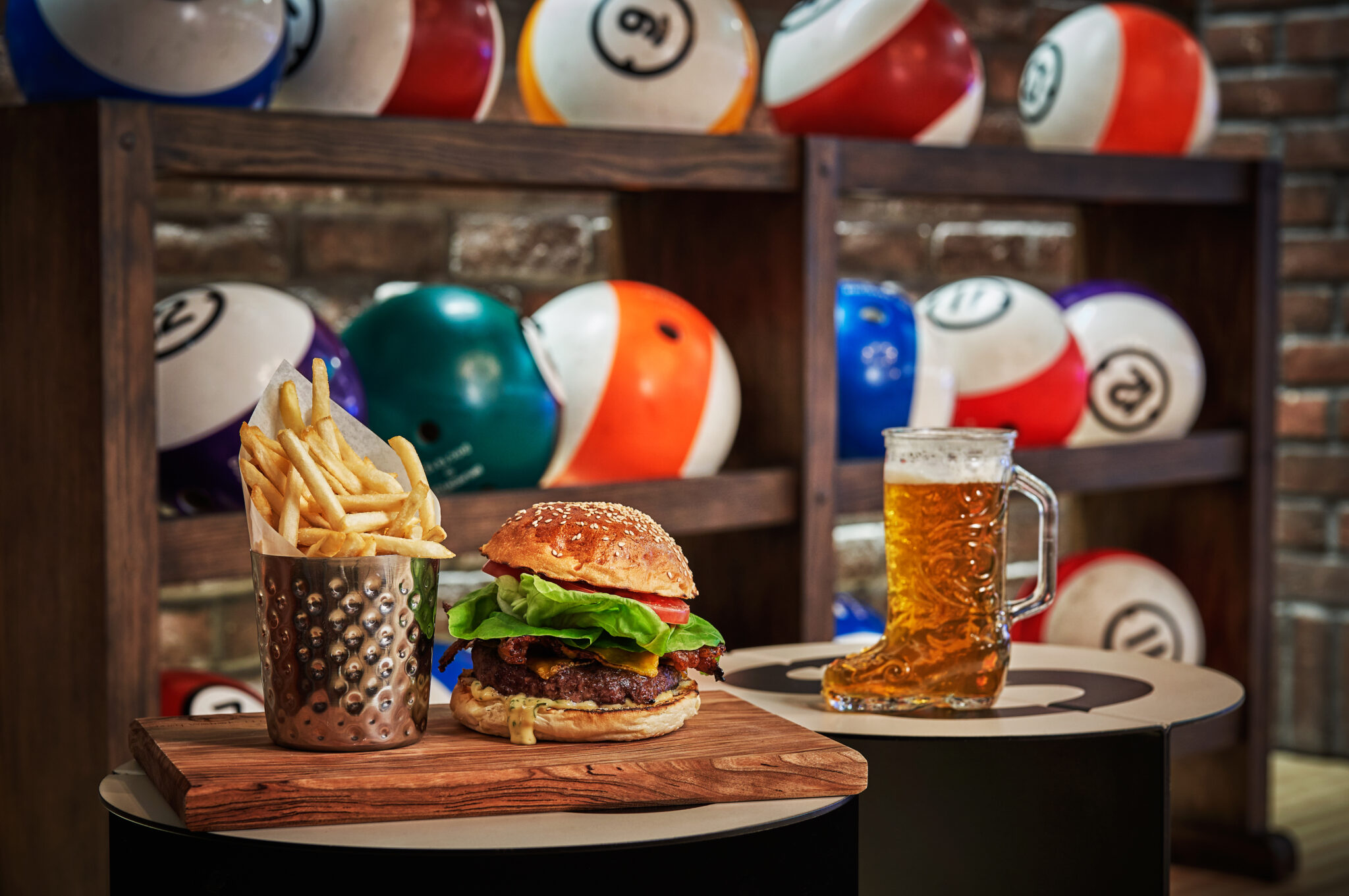 A beer in a glass boot next to a burger and fries