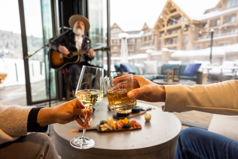 Two cocktails cheersing while a man is performing in the background