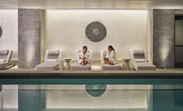 A couple in spa robes sitting by the Spa Montage Big Sky pool