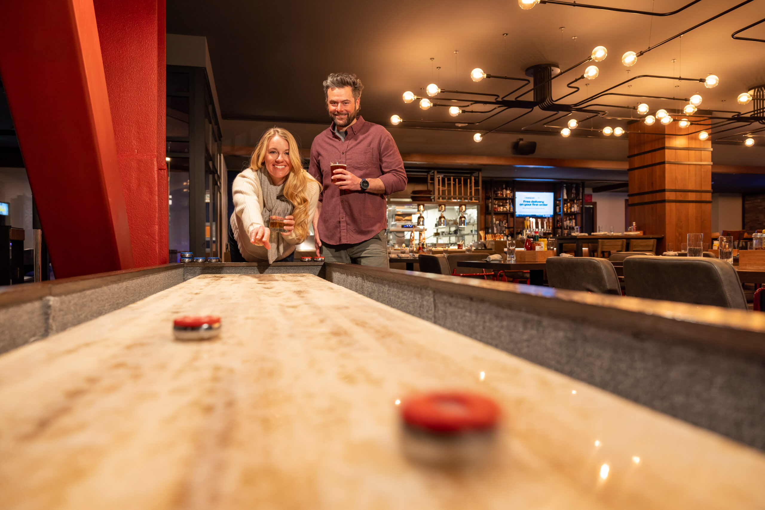 A couple playing shuffleboard at Beartooth Pub in Big Sky