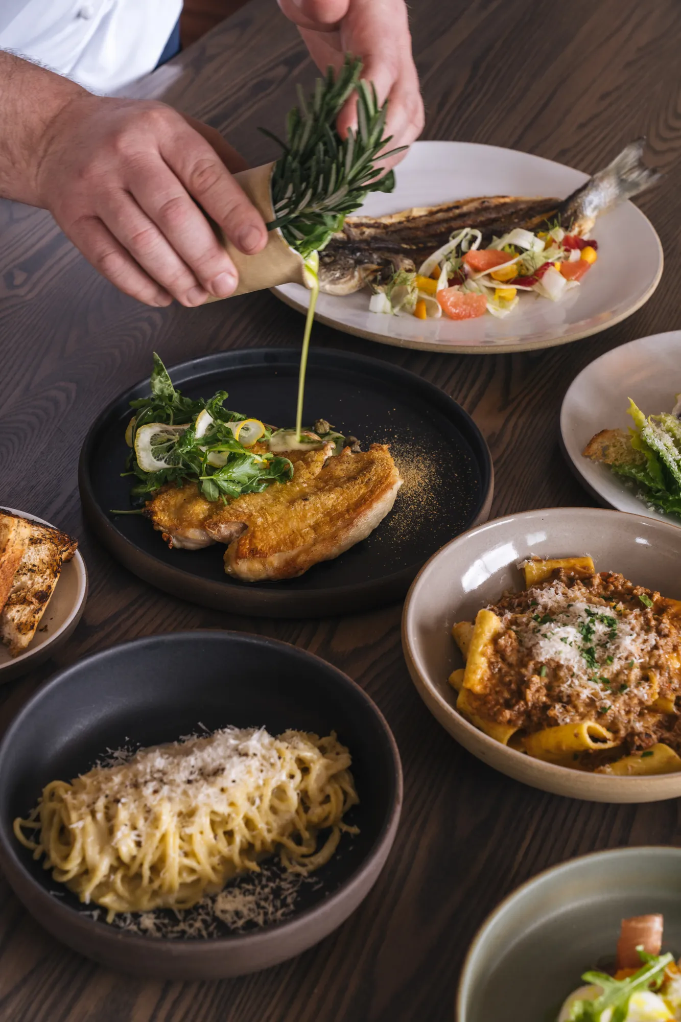 Dishes being plated by a chef at Cortina