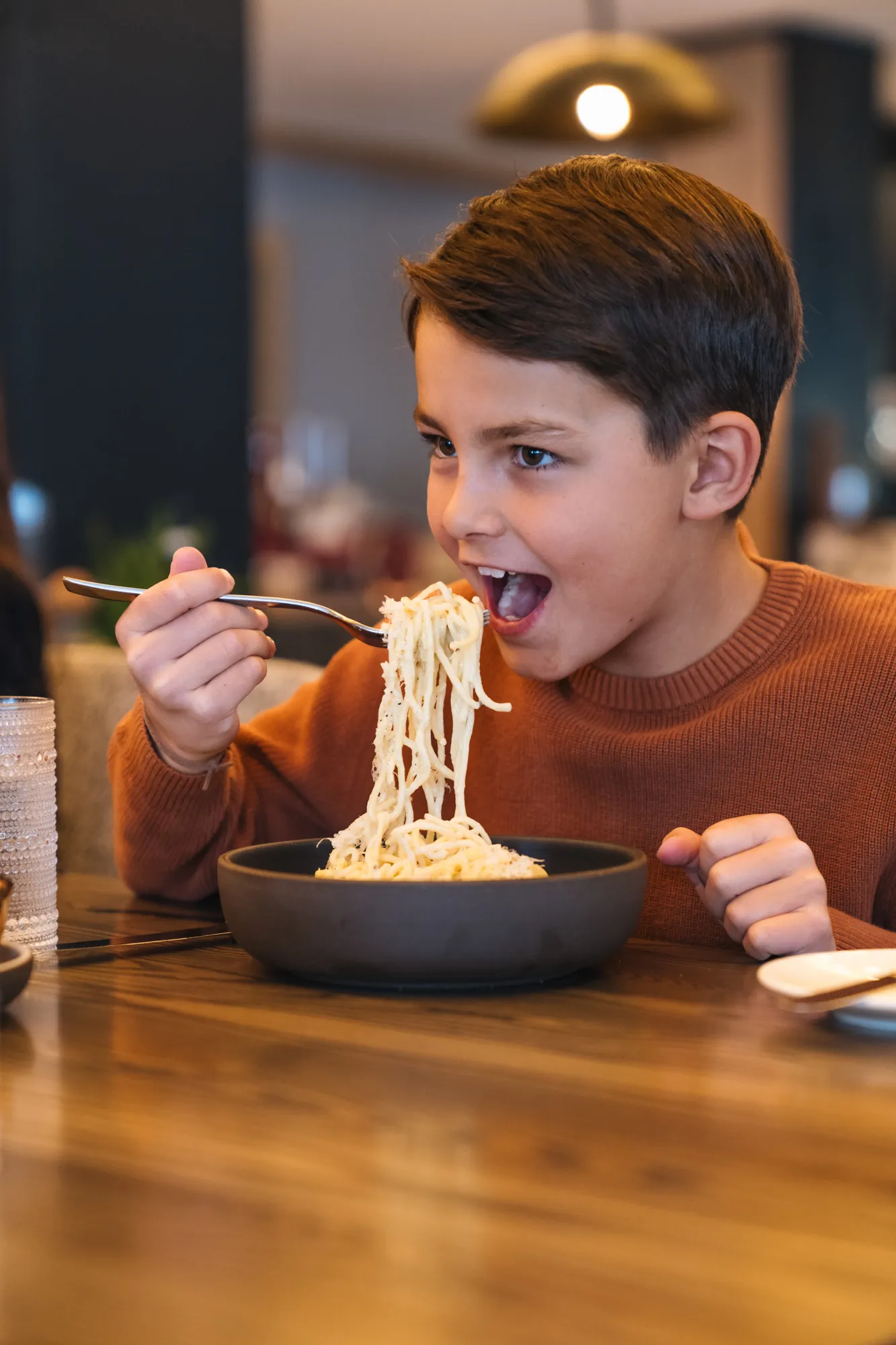 A child eating a plate of pasta at Cortina