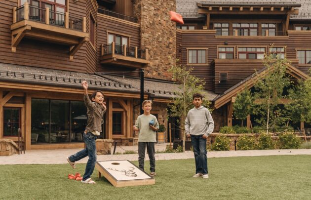 Three kids playing cornhole