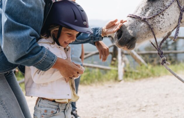 Child smiling while petting a horse