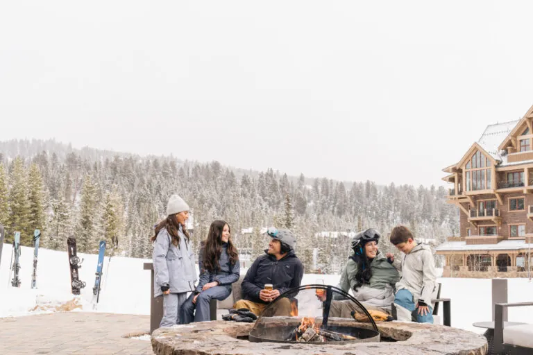 A family sitting by a firepit in sky clothes