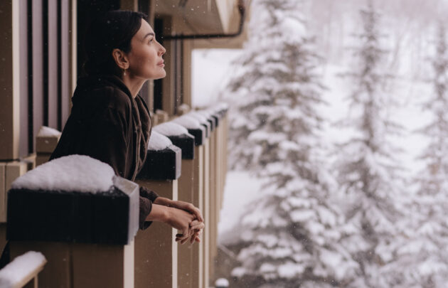 A woman watching the snow fall from her room at Montage Deer Valley