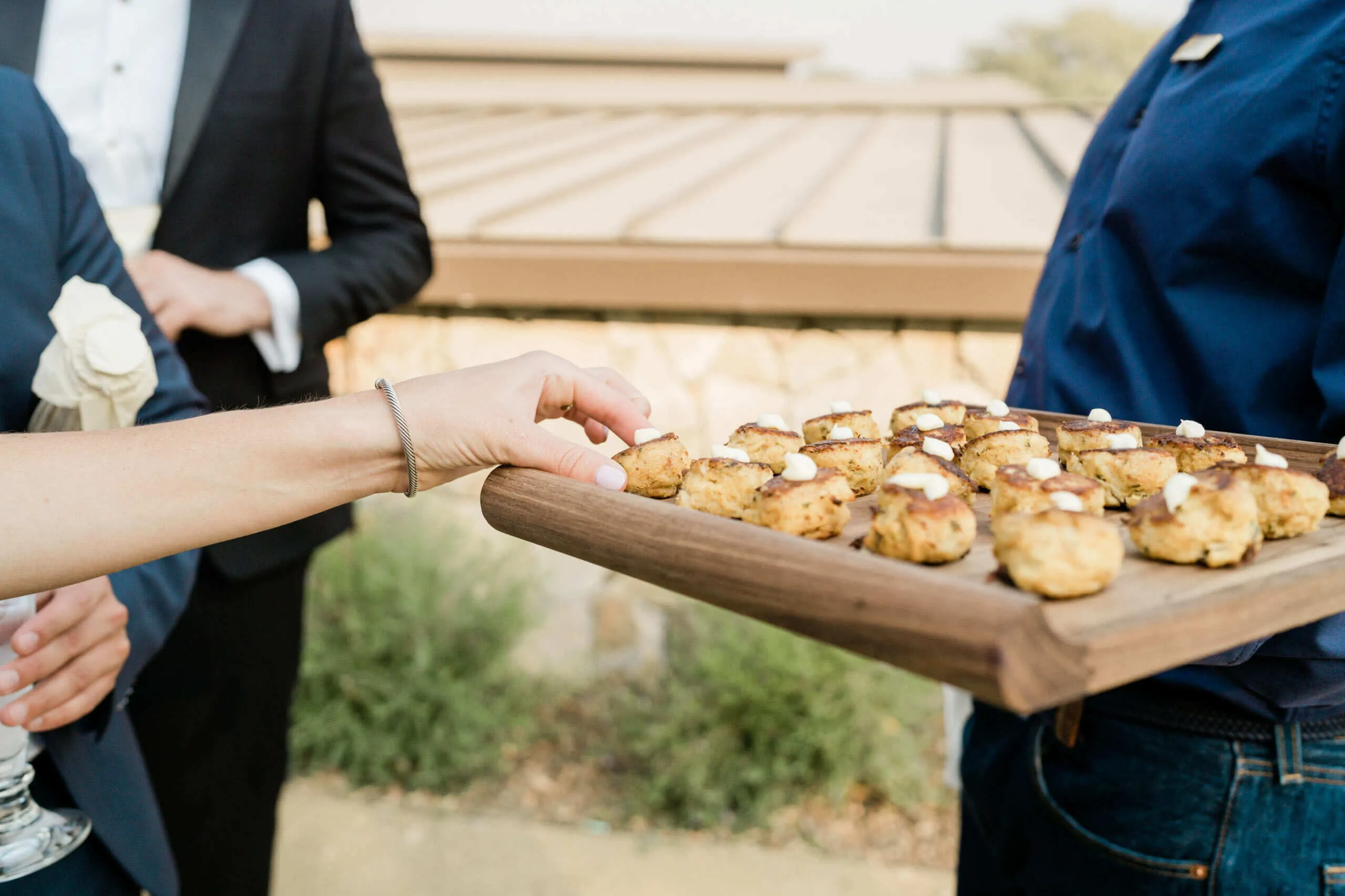 hand reaching for appetizer on wood platter