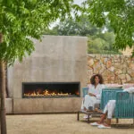 A couple wearing white robes sitting in blue chairs in front of fireplace