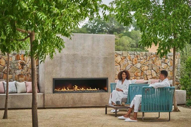 A couple resting outside a fireplace at wellness Spa Montage Healdsburg, at a luxury hotel