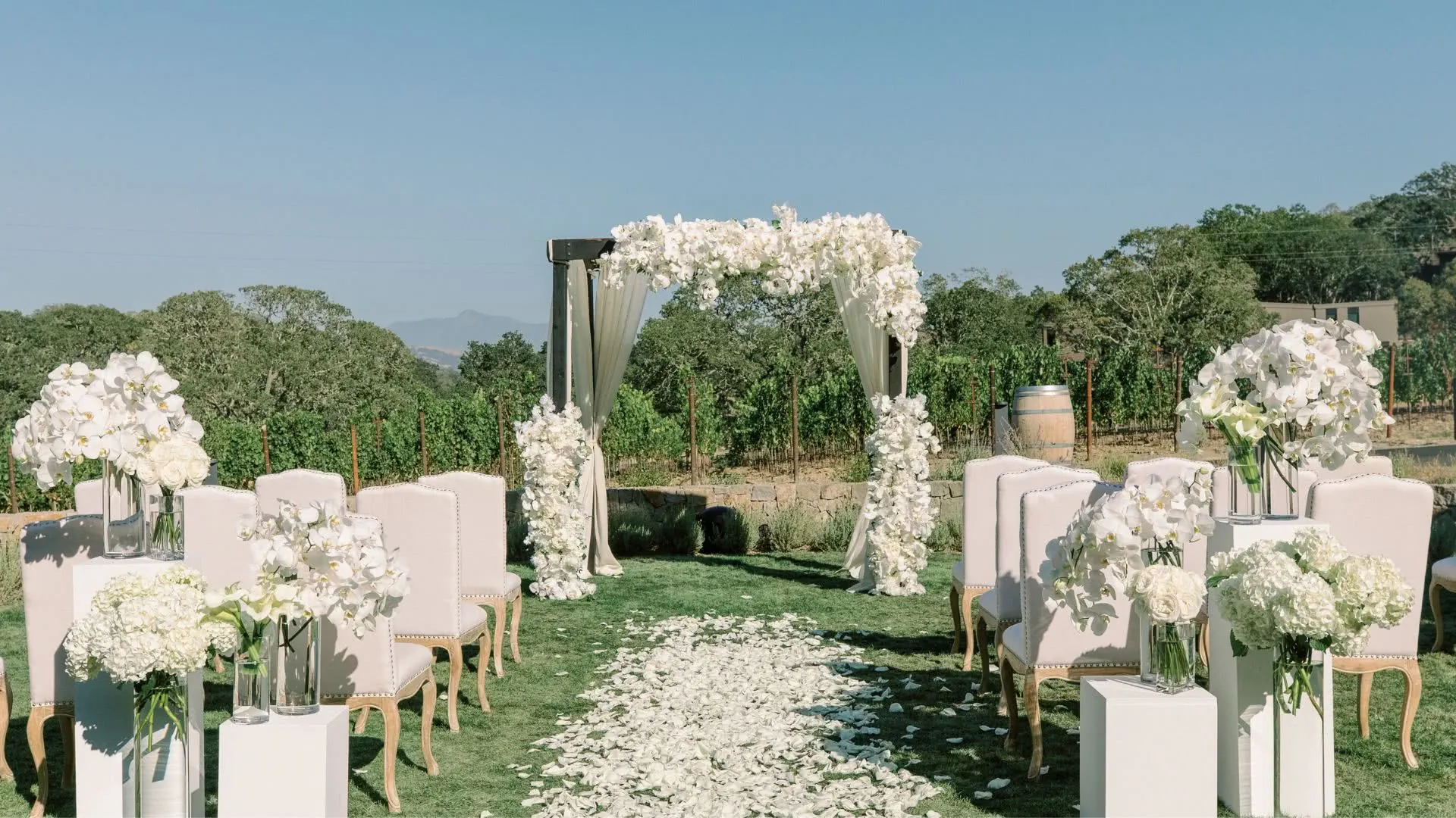 A wedding ceremony set up at Montage Healdsburg's Vista Lawn with white flowers and chairs.