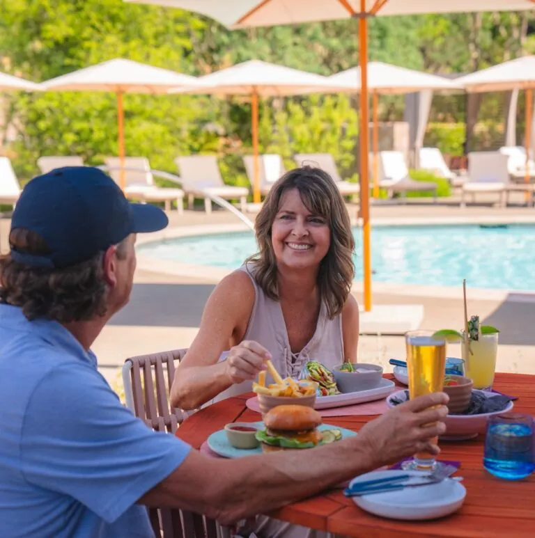 Couple eating at a table with the family pool in the background.