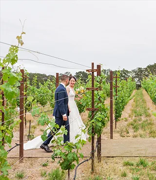 A bride and groom walking in a vineyard