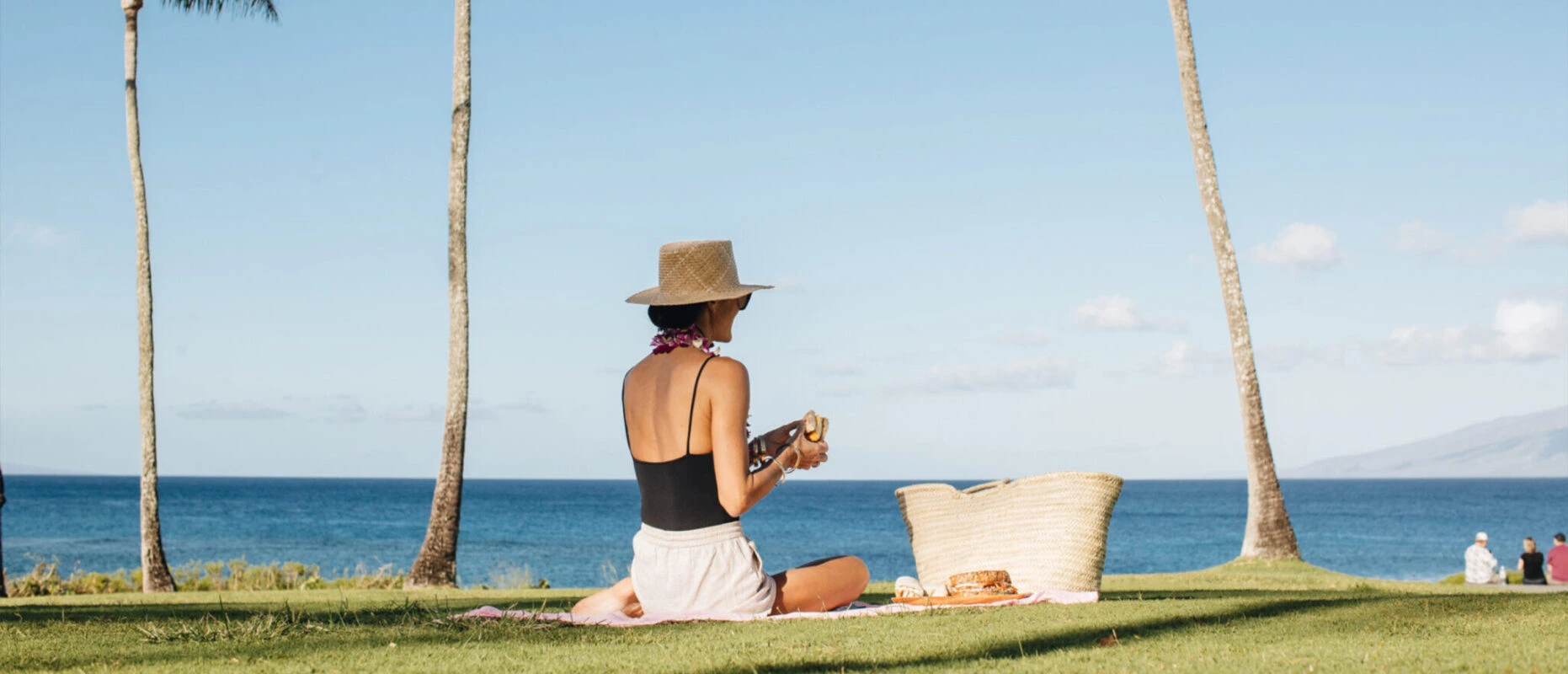 A woman having a picnic on the lawn at Montage Kapalua Bay