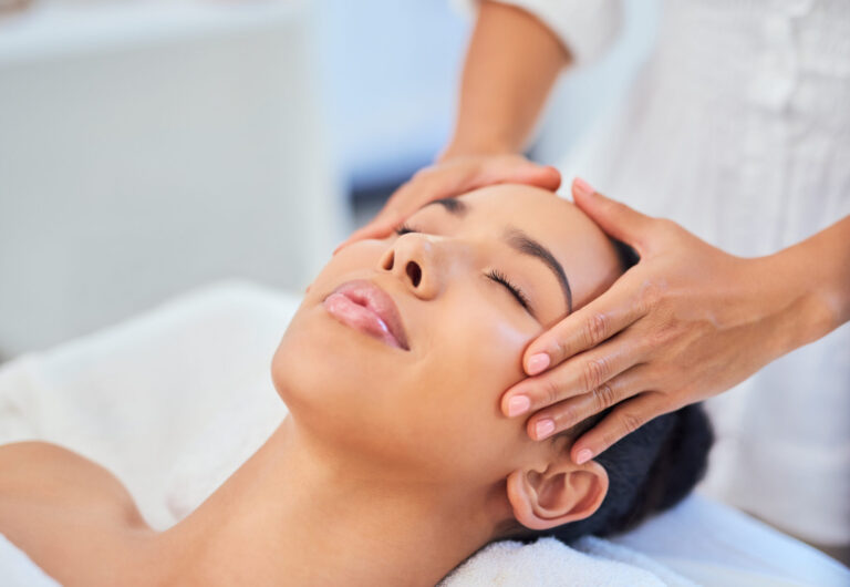 Woman gets face or facial massage at spa from beauty therapist at beauty salon for skin health and wellness treatment.