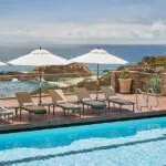 Pool at Montage Laguna Beach resort with lounge chairs and umbrellas set up, with ocean views