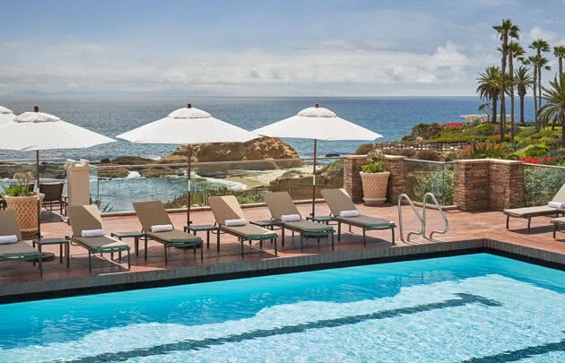 Pool at Montage Laguna Beach resort with lounge chairs and umbrellas set up, with ocean views