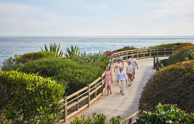 Family walking by ocean across bridge pathway at a luxury Laguna Beach resort