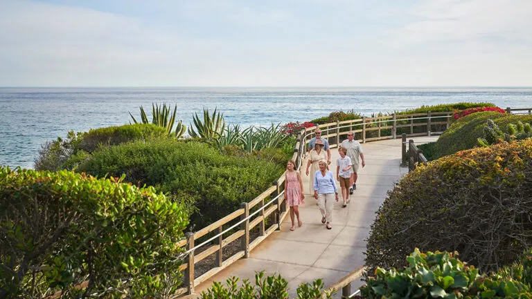 Family walking by ocean across bridge pathway at a luxury Laguna Beach resort