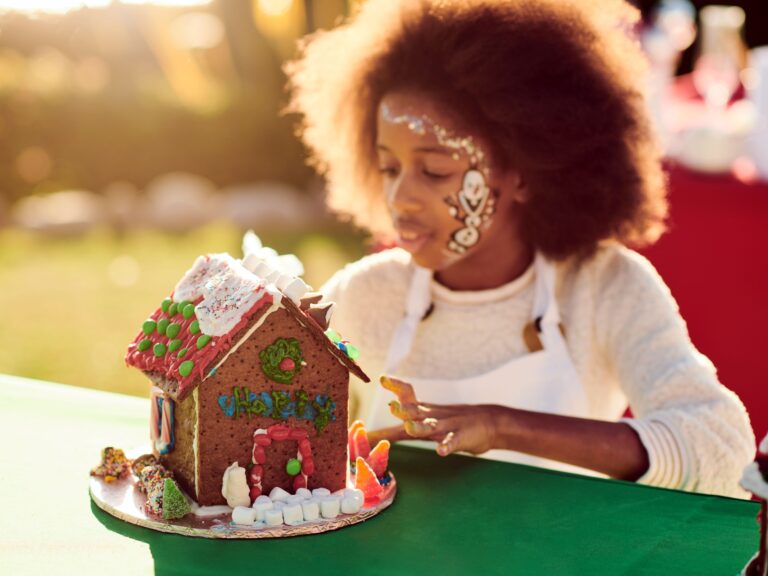 A child is decorating a gingerbread house