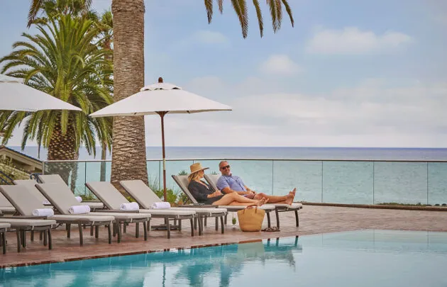 A couple lounging by the pool overlooking the ocean