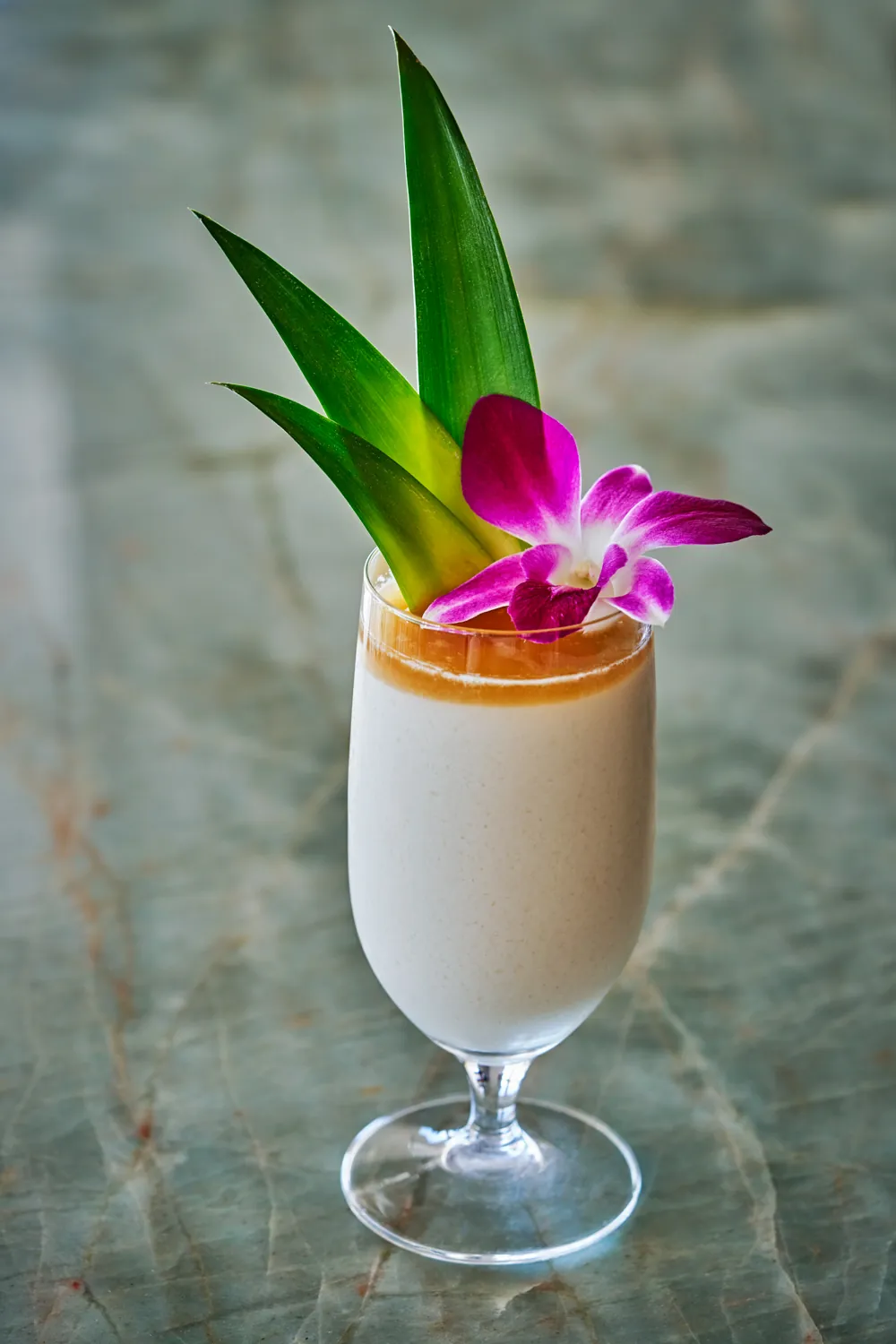 Creamy cocktail with floral garnish at Mosaic