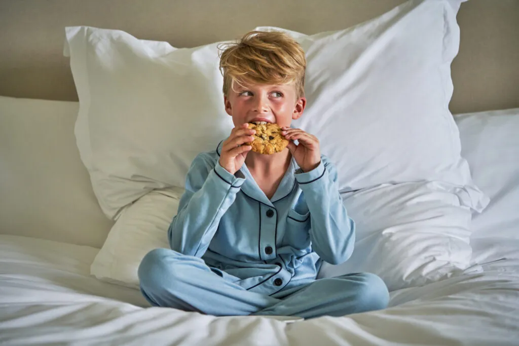 A child eating a cookie in bed at Montage Laguna Beach
