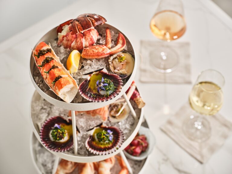 Tiered seafood platter with wine glasses on a marble table.