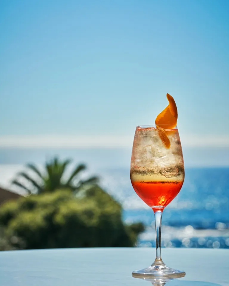 Cocktail with orange garnish by the ocean
