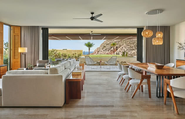 Montage Los Cabos guest room highlighting the living room with couch, dining table, and open door