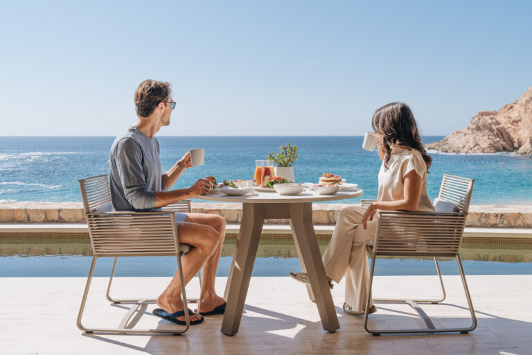 Couple eating breakfast on guestroom patio.