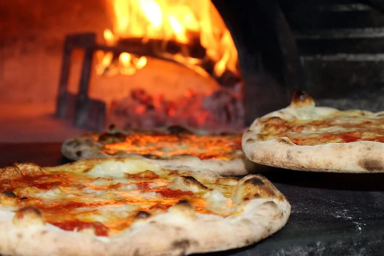 Two pizzas sitting next to each other in front of an oven