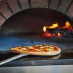 Pizza being taken out of wood-fired brick over at FLAME