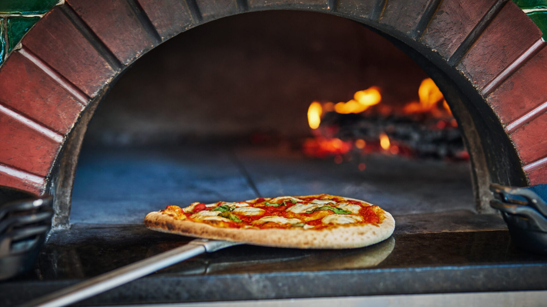 Pizza being taken out of wood-fired brick over at FLAME