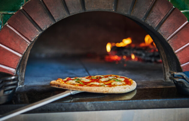 Pizza being taken out of wood-fired brick over at FLAME