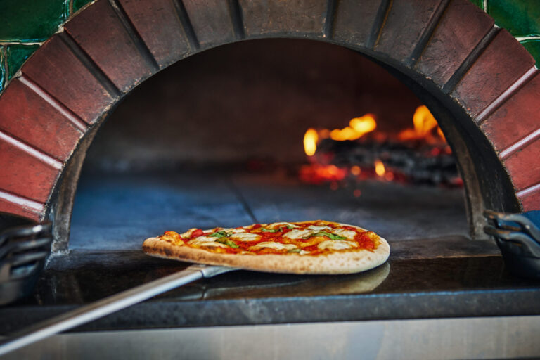 Pizza being taken out of wood-fired brick over at FLAME