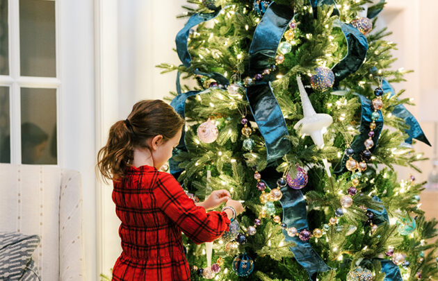 A child hanging an ornament on a Christmas tree