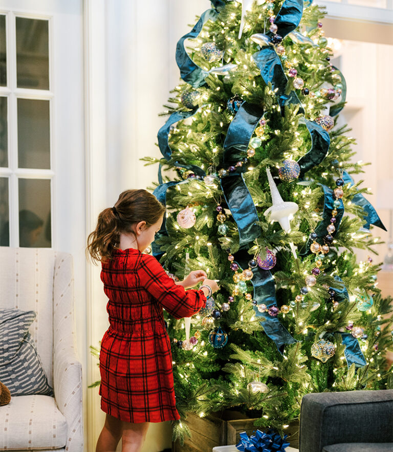 A child hanging an ornament on a Christmas tree