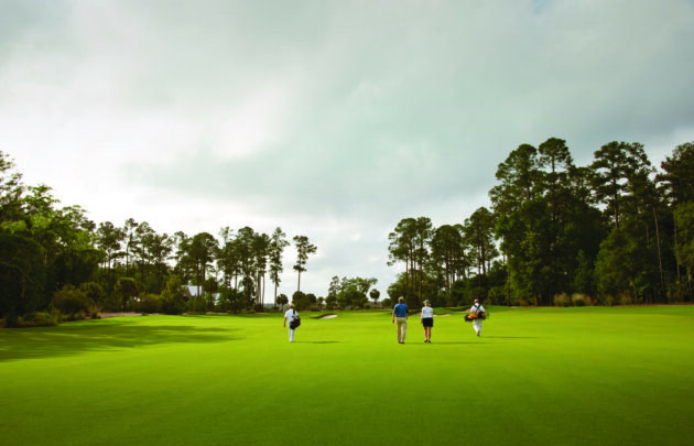 Four people walking on a golf course at Montage Palmetto Bluff