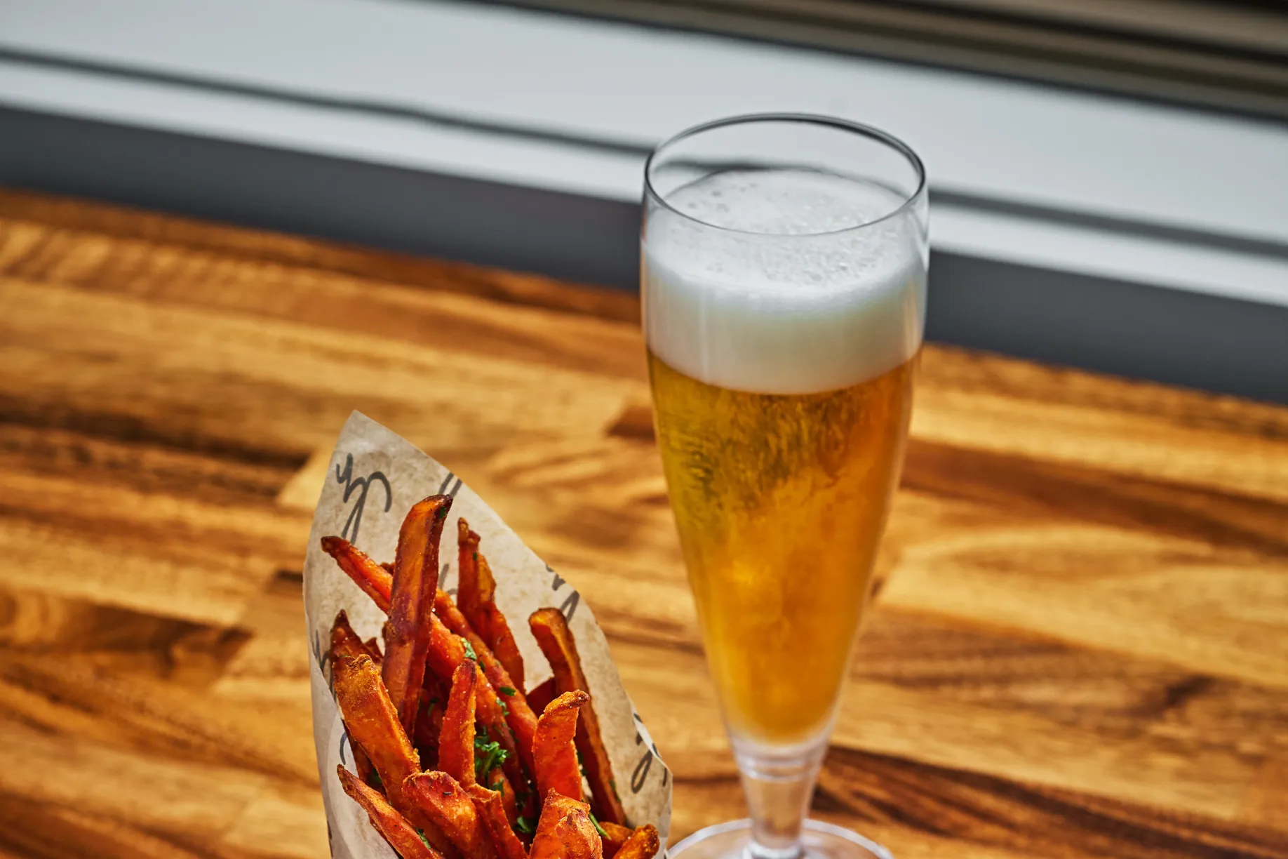 A beer and fries on a wooden table